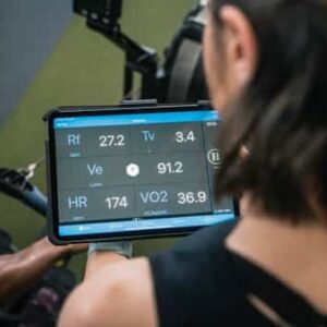 Adult man reviewing fitness metrics on a tablet during a workout session at the gym.