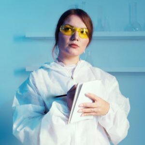 Confident female scientist in a lab coat taking notes in a laboratory.