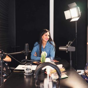 Three women engaged in a lively podcast discussion in a cozy indoor setting, fostering empowerment and connection.
