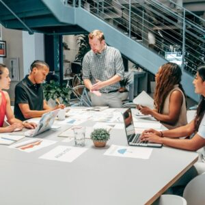 A diverse group of colleagues collaborating on a project in a modern office setting with laptops and documents.